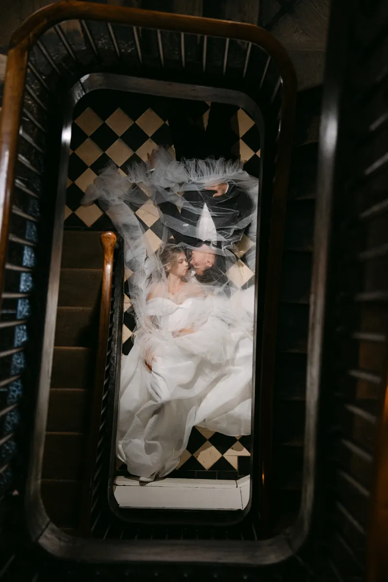 Braut im Treppenhaus eines Schlosses, von oben fotografiert