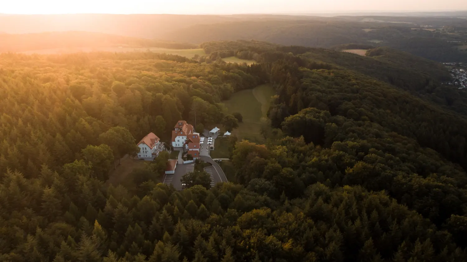 Luftaufnahme des Hohen Darsbergs in Neckarsteinach bei Sonnenuntergang, mitten im Wald über dem Neckartal