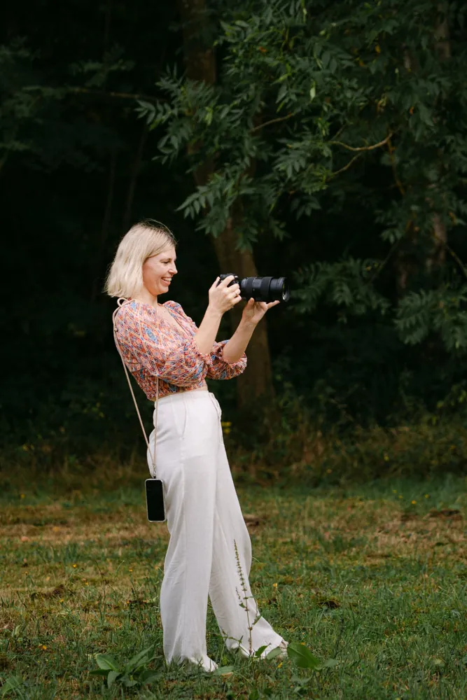 Lisa fotografiert lachend auf einer Wiese
